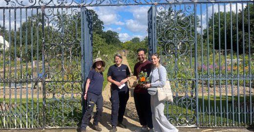 Group of 4 people in front of garden gates.