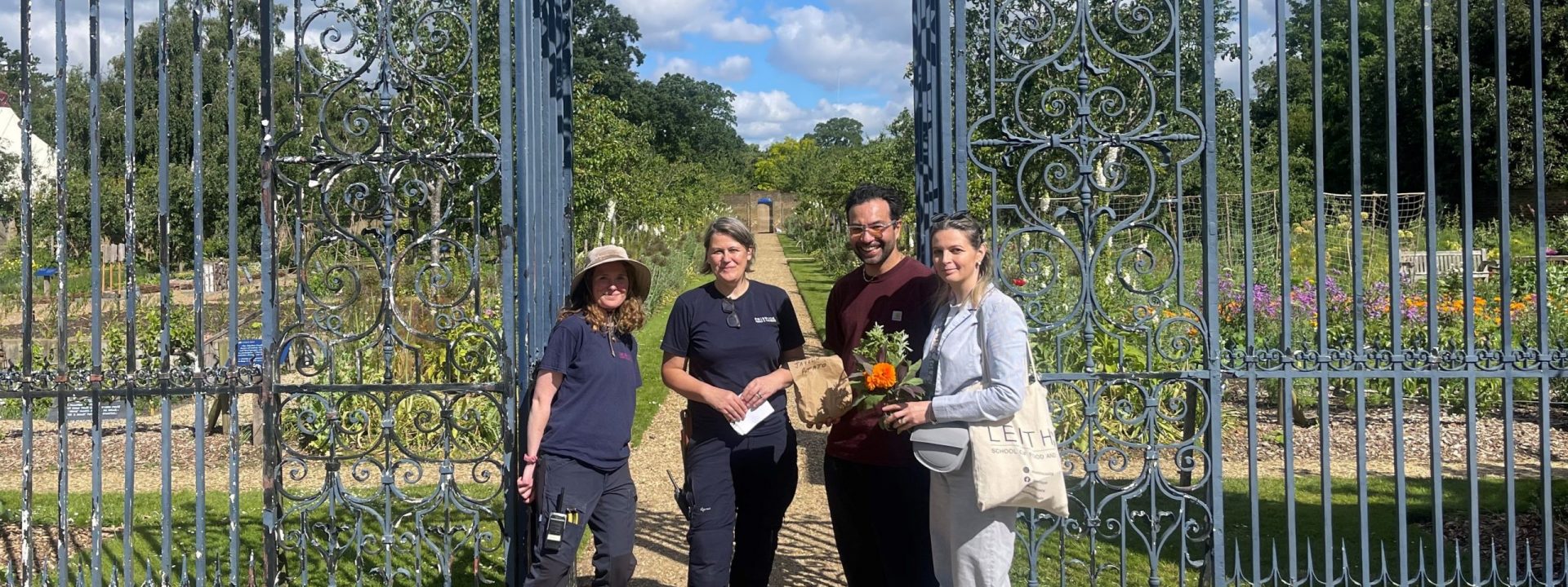 Group of 4 people in front of garden gates.